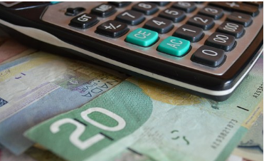 Image of a desk calculator with $25 Canadian under it.