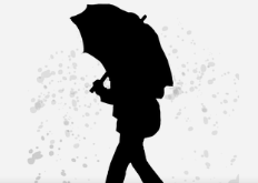 Silhouette of woman walking in rain covered by an umbrella.